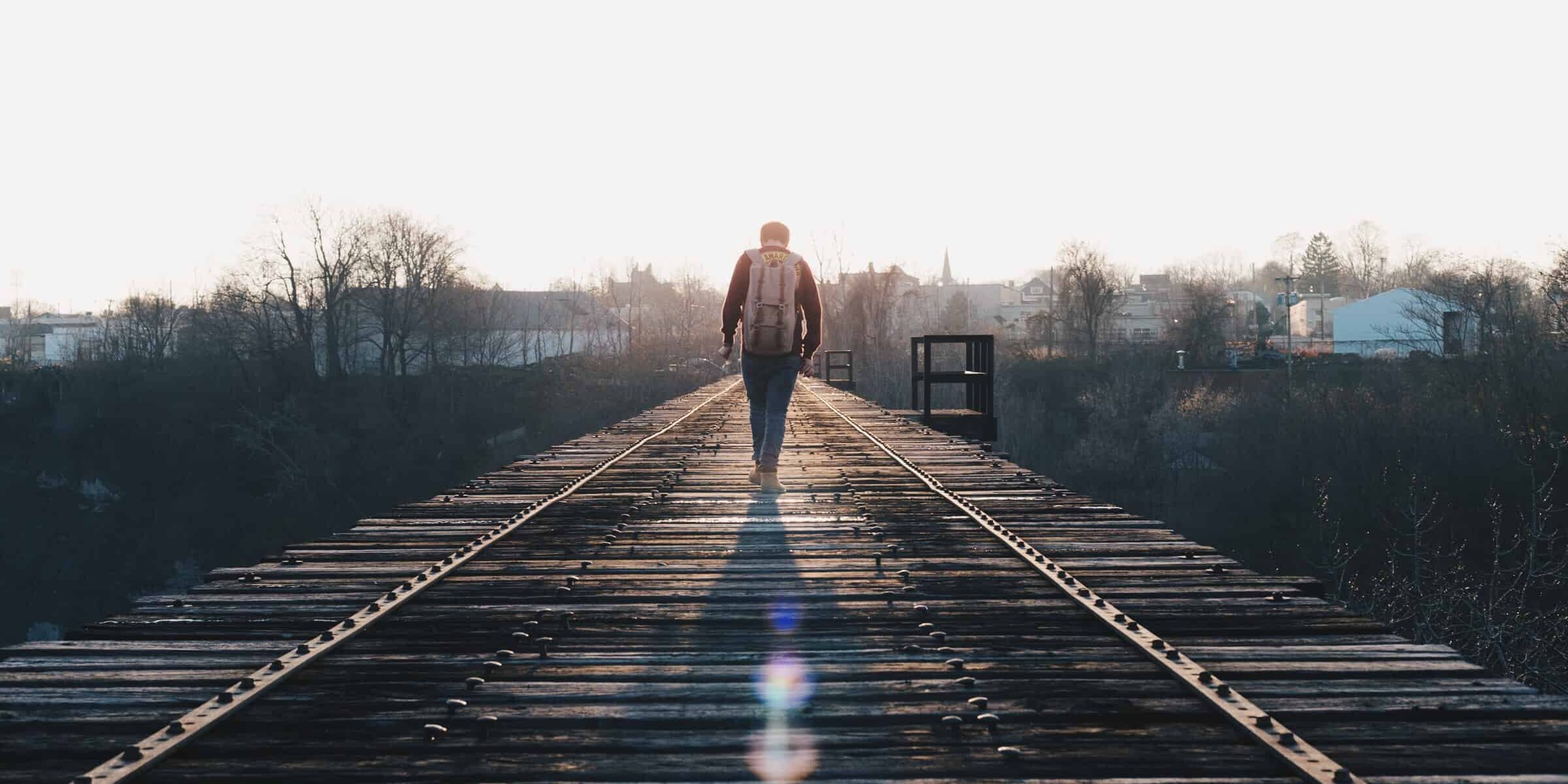 man walking in the middle of rail road