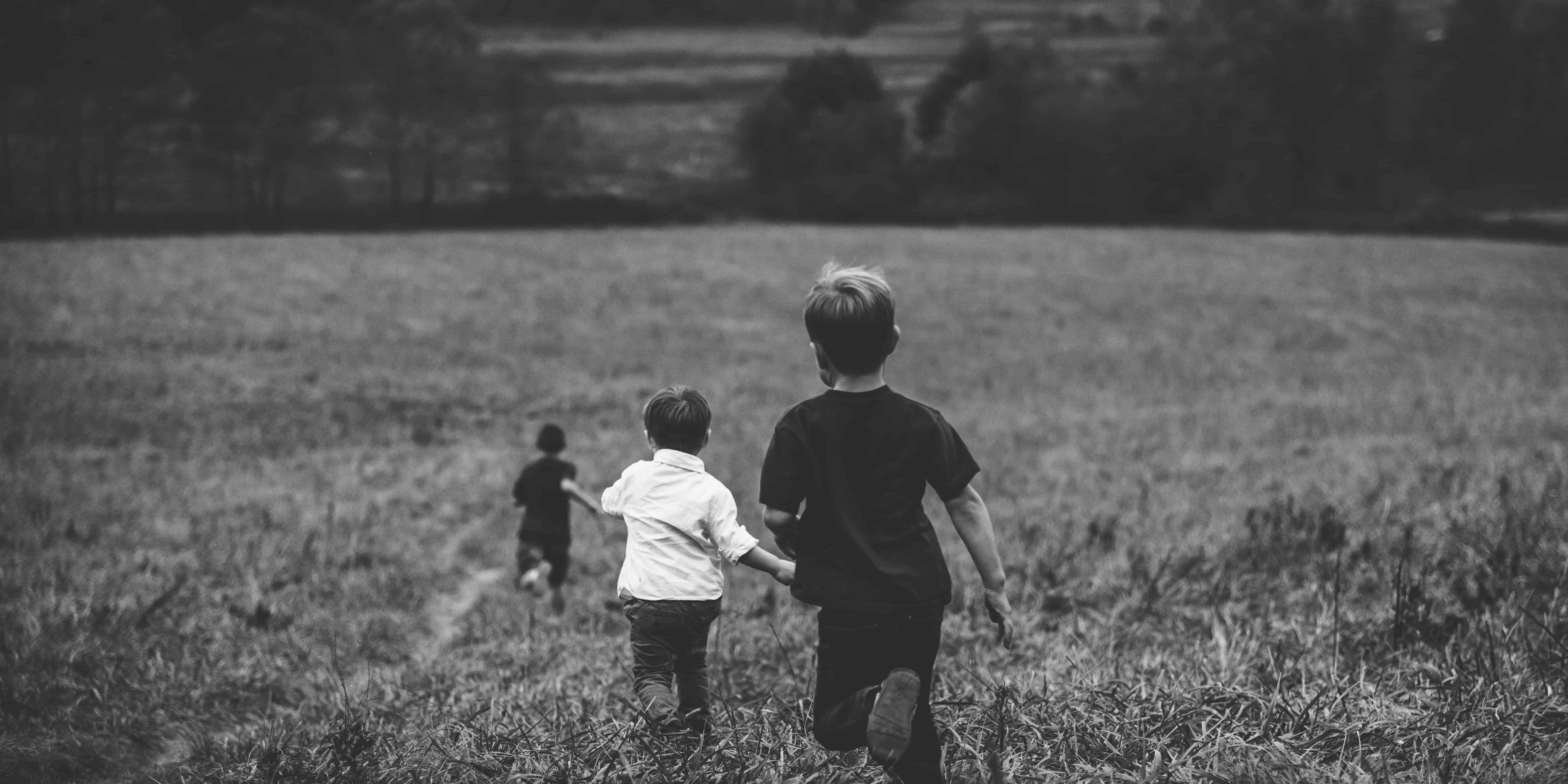 three boys running on field