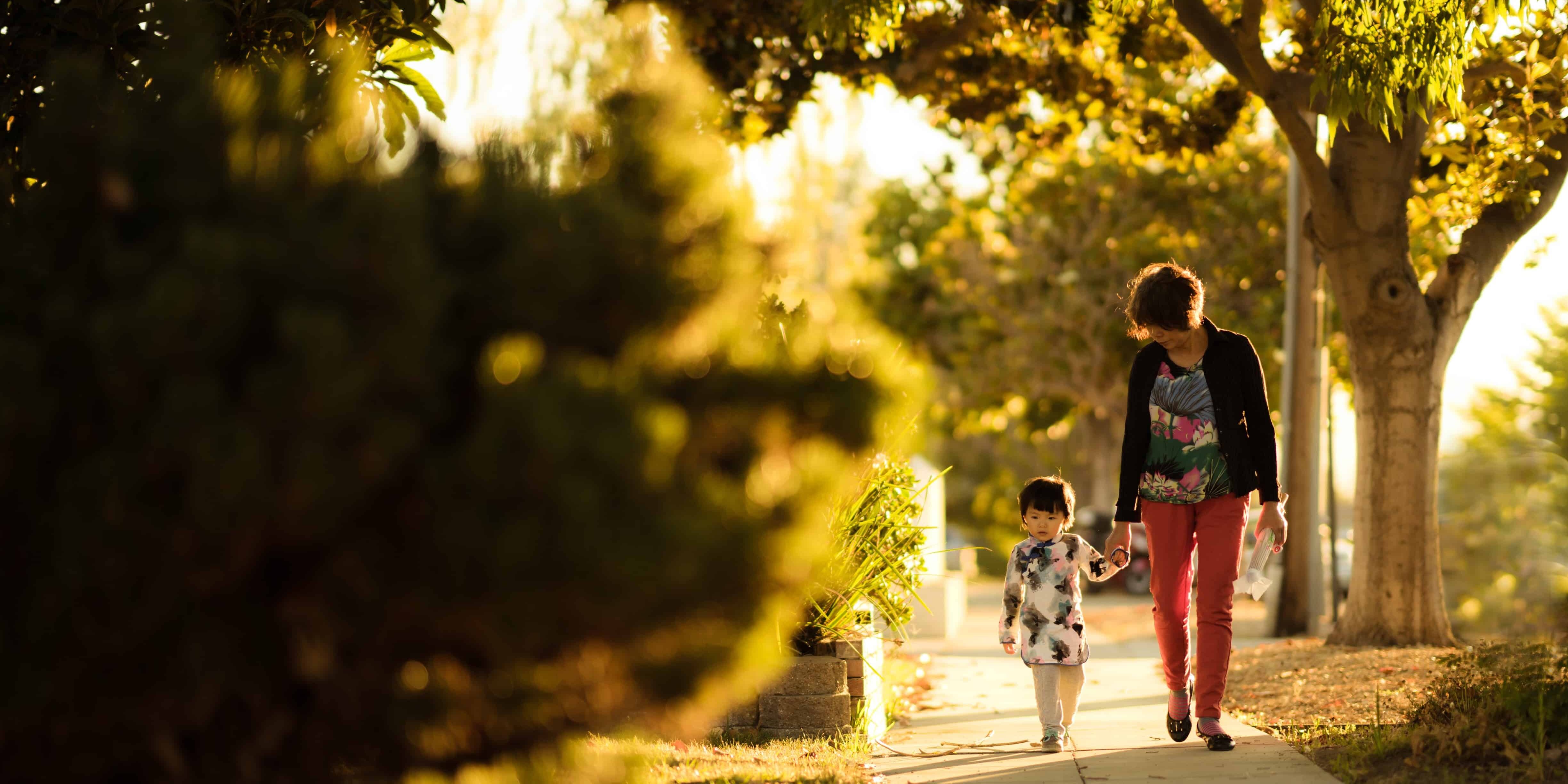 woman holding a child walking in the pathway
